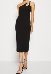Černé přiléhavé midi šaty s jedním ramínkem a stříbrným akcentem. Doplněné černými sandály na podpatku s ozdobným páskem s kamínky.