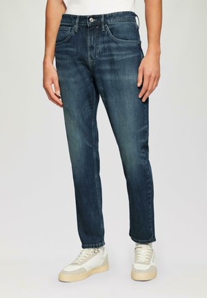 Jean en denim bleu foncé avec une coupe droite, présentant un design classique à cinq poches et un léger dégradé, complété par un système de fermeture à bouton.