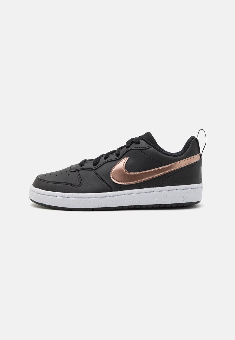 Fekete bőr sportcipők fehér középtalppal, rózsaarany Nike logóval és fekete fűzőkkel, kerek orral és sarokfüllel.