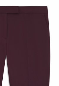 Bordowe spodnie w kant o gładkiej fakturze, z prostymi nogawkami i bocznymi kieszeniami dla zwiększenia funkcjonalności.