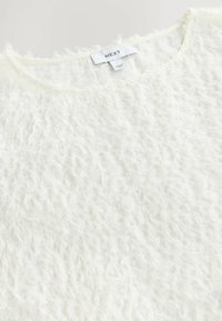 Maglione bianco, dalla consistenza soffice e pelosa, con scollo rotondo. Etichetta visibile, che indica il marchio "NEXT". Materiale morbido e dettagli di design a strati.