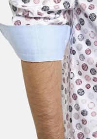 Kurzarmhemd aus weißen Stoff mit mehrfarbigen Punkten in verschiedenen Größen; blauer Kontrastbund. Strukturierter, leichter Stoff.