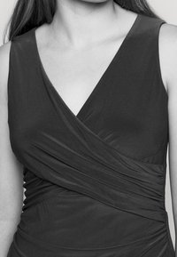 Black, sleeveless dress with a deep V-neck and gathered texture across the bodice. Fabric appears smooth and stretchy.
