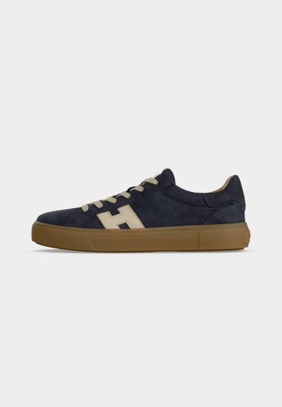 Baskets en daim bleu marine avec lacets beige clair et logo "H", dotées d'une semelle épaisse en caoutchouc marron, vues de côté sur fond blanc.