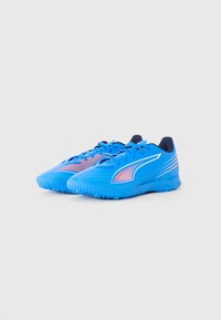 Une paire de chaussures de sport bleues avec des accents de rayures roses et blanches et un doublure intérieure sombre sur un fond clair.