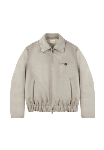 Beżowa kurtka zapinana na zamek o gładkiej fakturze, z kołnierzykiem, elastycznym dołem, bocznymi kieszeniami oraz małą kieszonką na piersi z guzikiem.