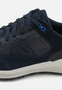 Sneaker in suede e pelle blu navy con accenti testurizzati, lacci rotondi e suola bianca imbottita con piccole perforazioni.