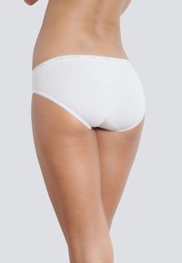 Slip in cotone bianco con una finitura liscia, caratterizzato da un delicato bordo di pizzo lungo la vita. Design semplice e aderente.