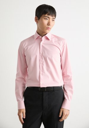 Roze overhemd met lange mouwen en knoopsluiting in een gladde stof met een puntige kraag, voorzien van witte knopen, gecombineerd met zwarte broek en een riem.