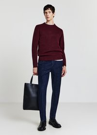 Bordeauxfarbener Strickpullover mit Rundhalsausschnitt, dunkelblaue Hose, schwarze Lederstiefel und eine schwarze Tote-Bag. Glatte Textur, enganliegendes Design.