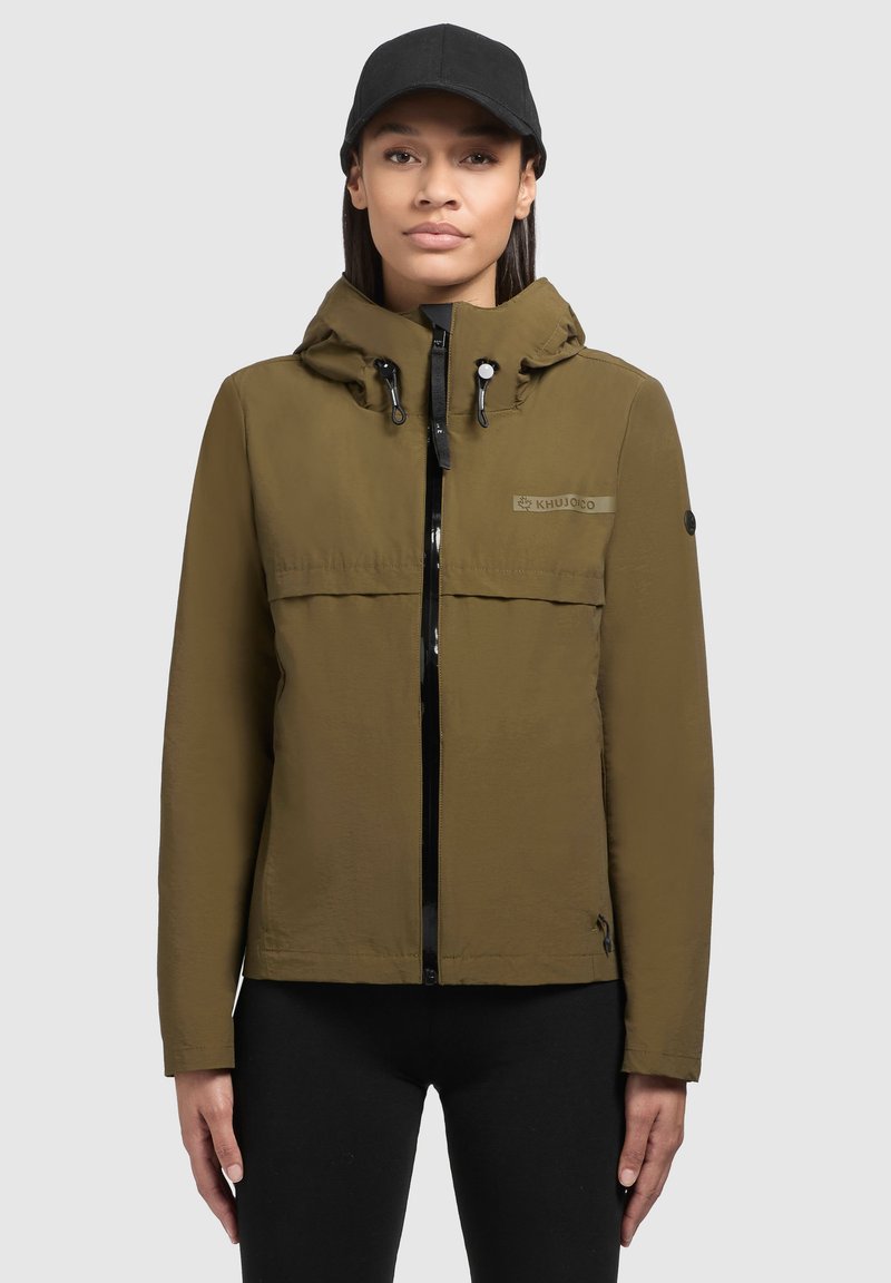 Giacca impermeabile verde oliva con chiusura a zip, cappuccio regolabile e dettaglio del logo. Presenta accenti neri e una vestibilità strutturata.