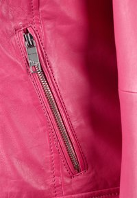 Ljust rosa läderjacka med en slimmad silhuett, metallic dragkedja och slät yta. Sömmarna är synliga längs med sömmarna.