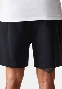 Pantaloni corti neri realizzati in un materiale morbido, con un taglio dritto, una vita elastica e senza motivi o dettagli in metallo visibili.