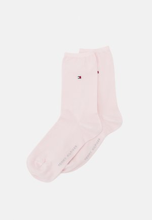 Light pink cotton socks featuring a small logo in red, white, and blue, with a smooth texture and ribbed tops. Brand name printed on the sole.