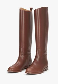 Brązowe skórzane kozaki do kolan o gładkim wykończeniu, płaskim obcasie oraz subtelnych przeszyciach po bokach i z przodu.