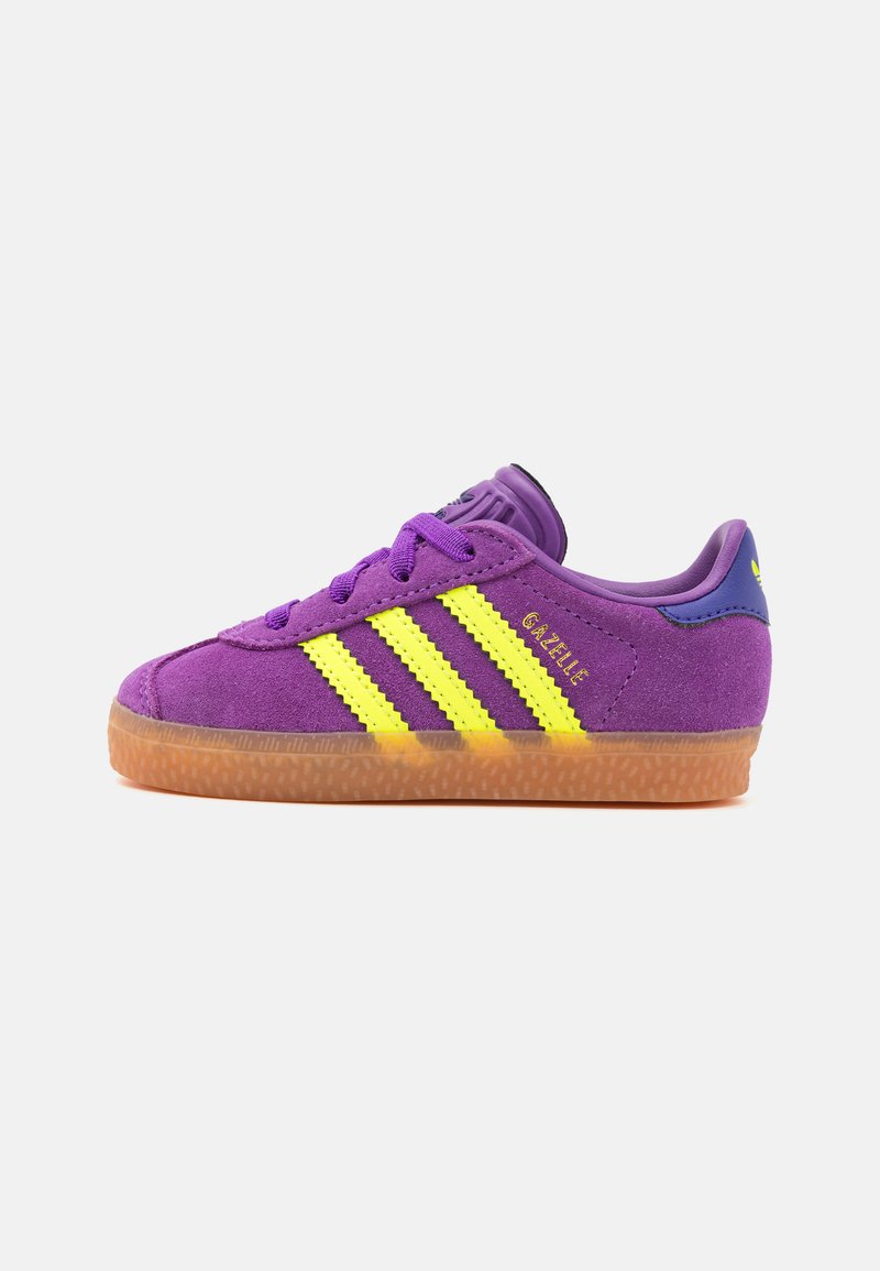 Fialové semišové tenisky so žltými pruhmi. Majú hnedú gumovú podrážku, zaoblenú špičku a polstrovaný golier. Na boku je logo "Gazelle".