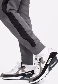 Nike Air Max neri, grigi e bianchi, realizzati in materiali a rete e camoscio, con un'imbottitura prominente, design con lacci e accenti con logo.