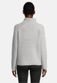 Ljusgrå stickad tröja med hög krage, ribbat mönster och långa ärmar. Har en avslappnad passform och raglansömmar.