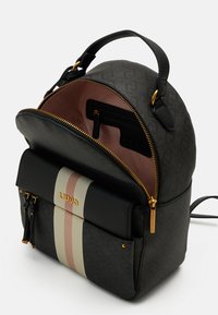 Sac à dos en cuir noir de forme arrondie, avec des accessoires dorés et une poche avant présentant des rayures horizontales en crème, rose et noir.