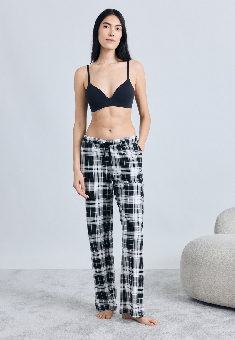 Svart bralette och svartvita rutig pyjamasbyxor med elastisk midjeband, har en avslappnad passform och två sidofickor.