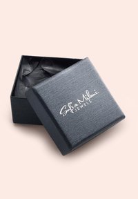 Svart texturerad smyckesask med ett gångjärnslock, som har en vit präglad logotyp "Sofia Milani Jewels" på framsidan, fylld med svart silkespapper.