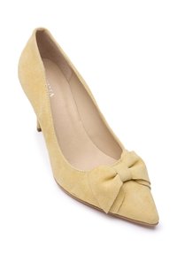Gele suède pump met een puntige neus en een strikje aan de voorkant. De hak is kort met een glad ontwerp en een neutrale binnenkant.
