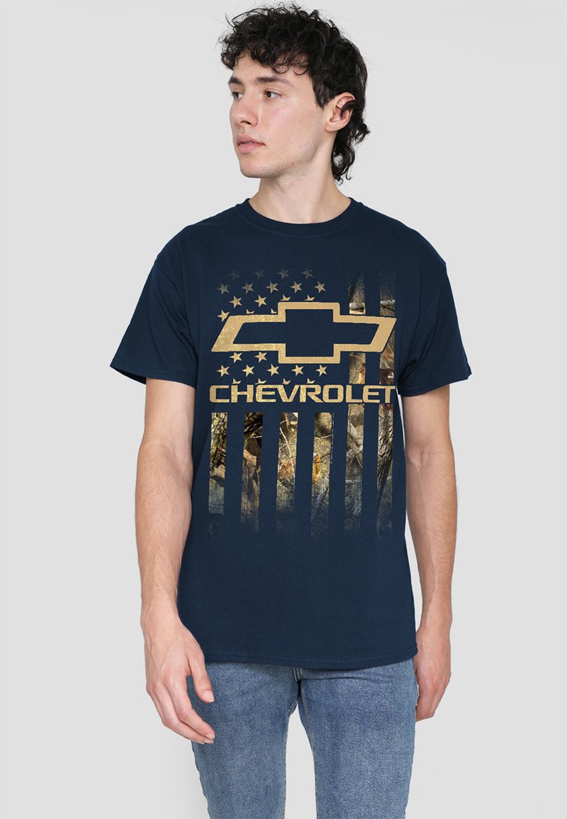 Navy blue cotton T-shirt featuring a large gold Chevrolet logo and a camouflage texture resembling an American flag. Short sleeves, crew neck.