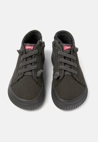 Scarpe di tela nere con finitura testurizzata, dotate di lacci rotondi, colletto imbottito e suola in gomma con scanalature. Logo "Camper" sulla linguetta.