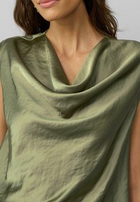 Cowl-neck top in olijfgroen satijn, met een gladde textuur en gedrapeerd ontwerp, korte mouwen en een subtiele glans.