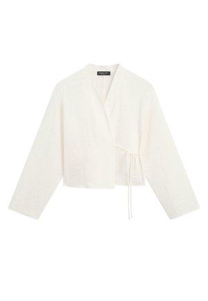 Pull court portefeuille blanc à manches longues, col en V et fermeture nouée sur le côté, tissu texturé et coupe décontractée.