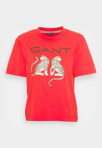 Rød bomulds T-shirt med rund halsudskæring og korte ærmer. Har et grafisk motiv af to stribede tigre og brandnavnet "GANT" i grønt.