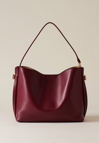 Borsa a mano in pelle bordeaux con una texture liscia, parte superiore arrotondata, tracolla singola e dettagli in metallo dorato sui lati.