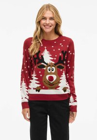 Punane kudumisse seljas, millel on joonis karikakra jõulunina, mustad sarved ja valged jõulupuud, kaunistatud pom-pomiga karikakra ninal.