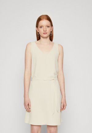 Robe crème sans manches avec un décolleté en V, texture douce, détail de ceinture à la taille et coupe fluide. Design simple au-dessus du genou sans embellissements.