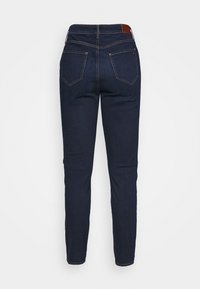 Dunkelblaue Jeans aus Denim mit glatter Textur, schlankem Schnitt, zwei Gesäßtaschen und einem kontrastierenden Lederpatch am Bund.