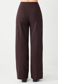 Wijde broek in donkerbruin stof, met een hoge taille, een gladde textuur en strakke lijnen zonder zichtbare patronen of accenten.