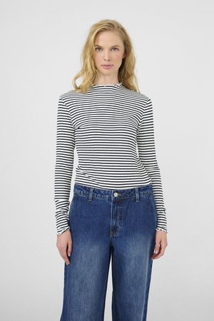 Riba tõmblukuga mustvalge pikakäisteline särk, millele on sobitatud kõrge vöökohaga sinised denim laiad püksid. Omab ribakujulist tekstuuri ja sakilisi mansette.