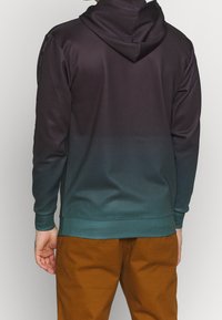 Felpa con cappuccio in gradiente di colore dal viola scuro al teal, realizzata in tessuto morbido. Presenta maniche lunghe e una vestibilità comoda.