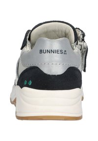 Børnesneakers i hvid og marineblå farvekombination, med overdel i ruskind og læder, justerbar strop og sål i gummirubber.