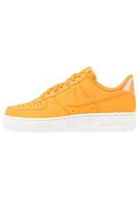 Baskets Nike Air Force 1 en cuir orange vif, avec une semelle en caoutchouc blanche, des perforations sur la boîte à orteils et des accents de logo emblématiques.