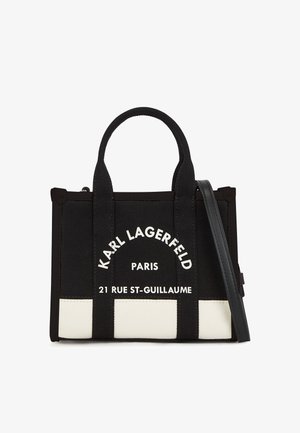 Bolso de lona negro con doble asa superior y correa desmontable. Presenta un estampado de logo blanco y un panel inferior en contraste. Forma rectangular.