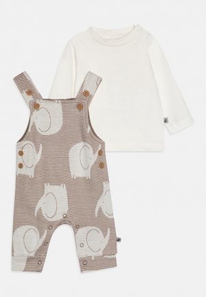 T-shirt blanc à manches longues pour bébé avec salopette beige présentant des motifs d’éléphants blancs et des boutons en bois.