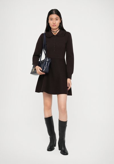 Robe longue marron à manches longues avec un col volanté et un devant boutonné, assortie à des bottes noires à talons jusqu'aux genoux et un petit sac à main bleu marine.