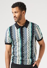 Pletená polo košile v barevném vzoru s modrými, zelenými a černými pruhy, krátkými rukávy a černým límečkem na knoflíkové zapínání.