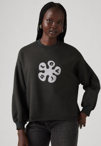 Dark green sweatshirt with long sleeves, crew neck, and a large white graphic logo in the center. Durable cotton material and relaxed fit.