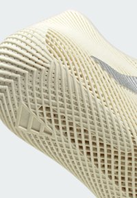 Nahaufnahme der beige strukturierten Sohle eines Sportschuhs mit Rastermuster und silbernem Nike-Swoosh-Logo.