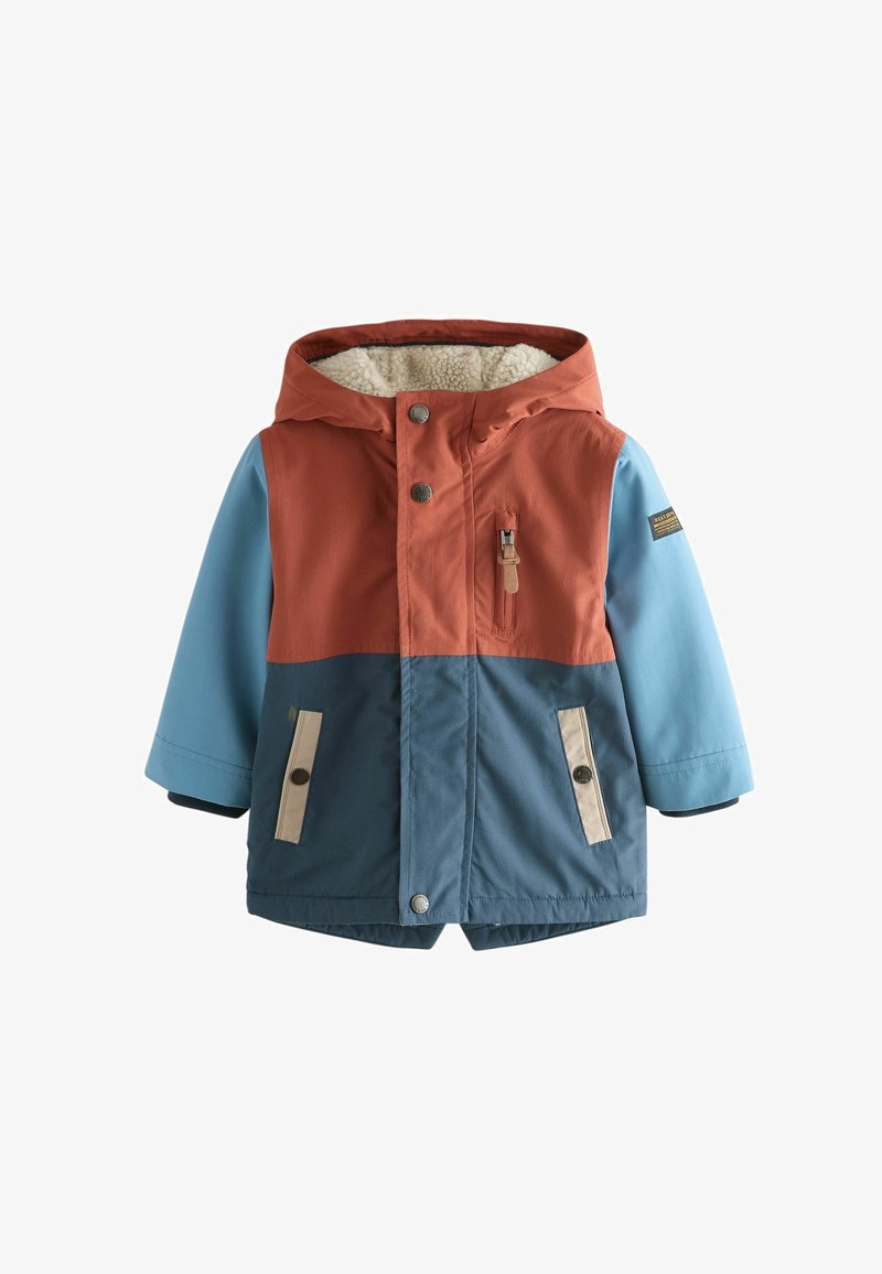 Veste d'hiver enfant à capuche avec des blocs de couleur orange rouille, bleu clair et bleu foncé, poches avant et doublure polaire blanche douce à l'intérieur de la capuche.