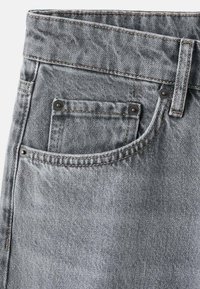 Vaqueros de mezclilla gris con un diseño clásico de cinco bolsillos, que incluyen un bolsillo pequeño delantero y costuras a contraste. Tejido texturizado y herrajes resistentes.