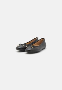 Des ballerines en cuir noir présentent un bout arrondi, un petit nœud avec des accents dorés, et une doublure intérieure douce. Design à semelle plate.