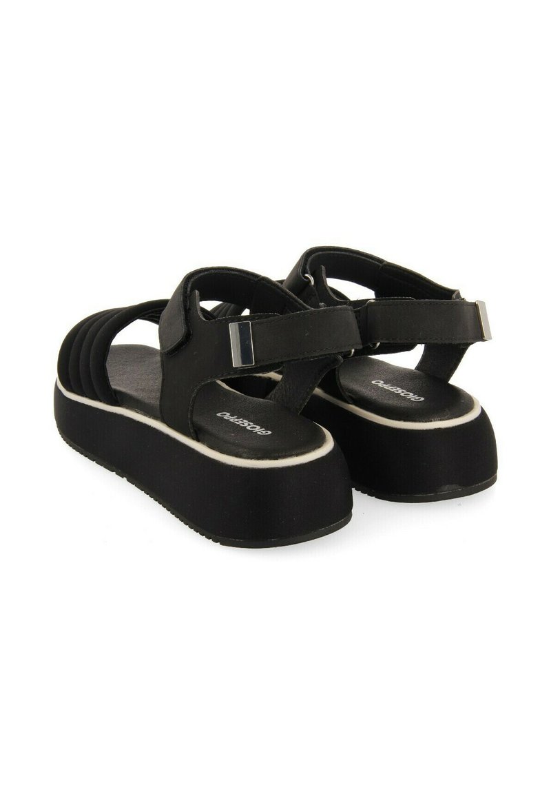 Sandalias de plataforma negras hechas de tela con una textura suave. Cuentan con correas ajustables, herrajes plateados y un borde blanco en la suela.
